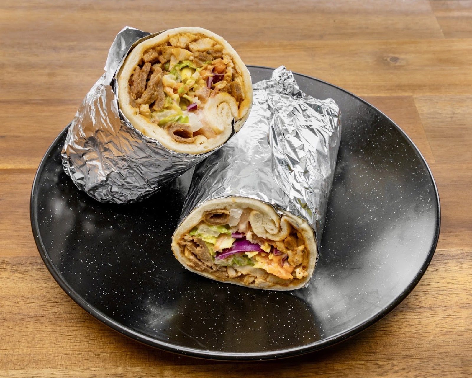 Doner kebab wrap cut open, filled with meat, salad and sauce